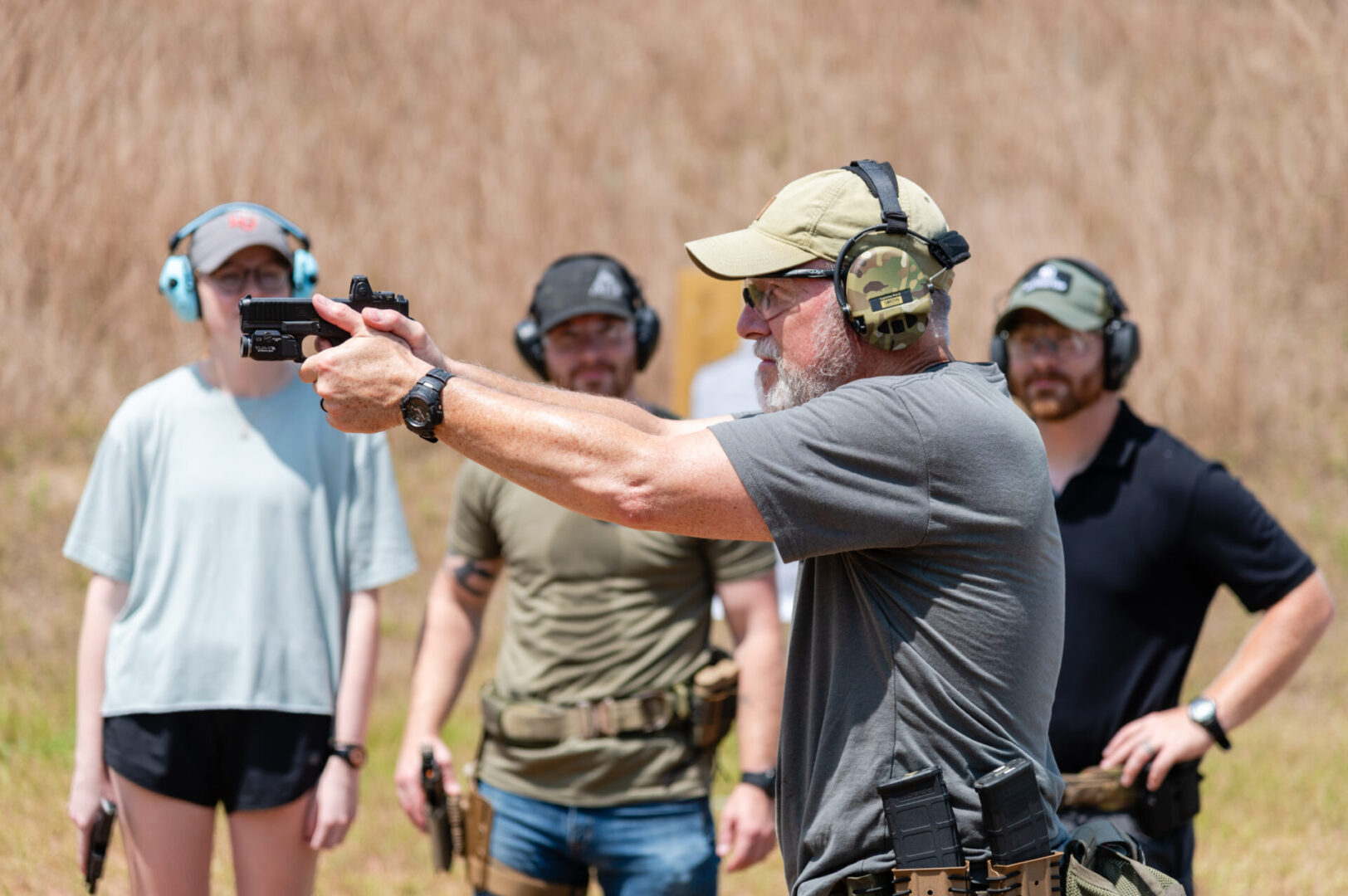 A man in grey shirt holding a gun.